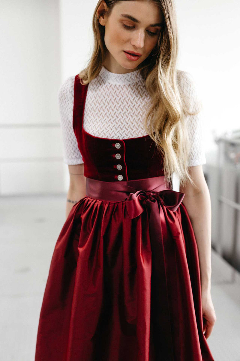 Rotes Samtdirndl mit klassischer Knopfleiste mit Münzknöpfen und roter Seidenschürze.